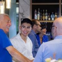 3 men smiling around a table